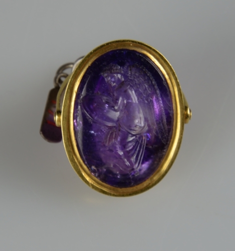 Front face of ring displaying engraving in purple stone.