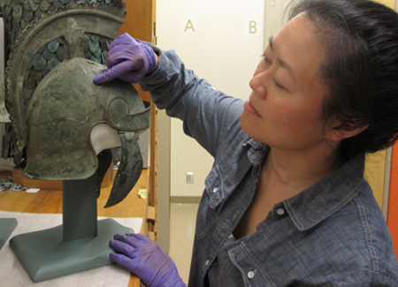 A woman examines a helmet inside the ROM's storage rooms.