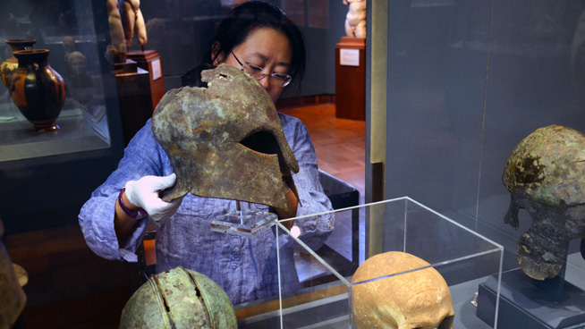 Kay Sunahara of the ROM's Greek & Roman section removing a Corinthian helmet from the gallery for study.