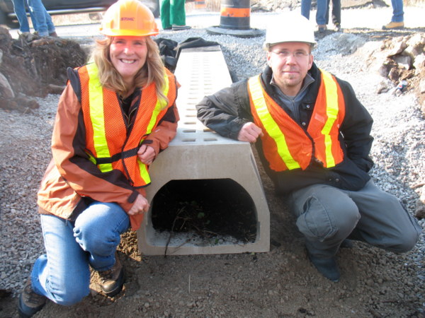 Two people stand beside an ecopassage, designed to facilitate wildlife crossing under roads.
