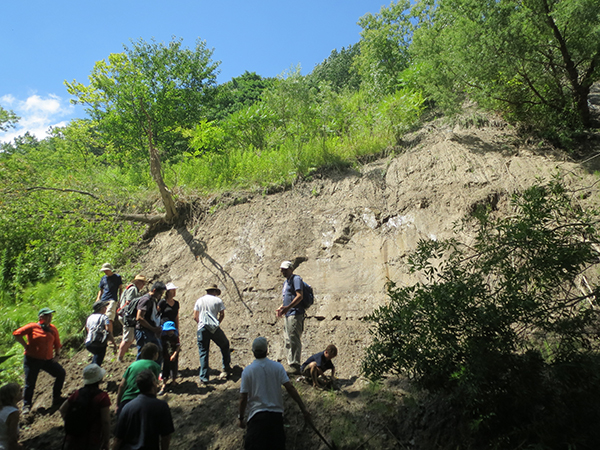 Group stands in fron of an exposed rock wall.