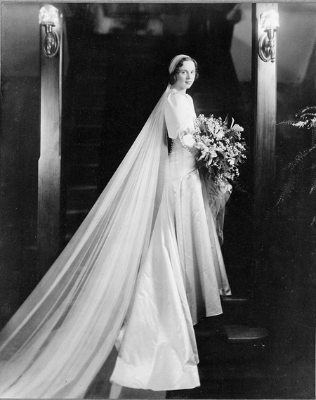 Portrait of bride in wedding gown standing on stairs.