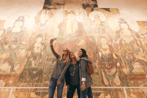 Photo of women taking a selfie in front of a mural