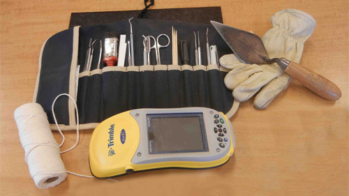 Modern tools used by archaeologists: gloves, trowel, brushes and electronic tools such as Global Positioning System (GPS).