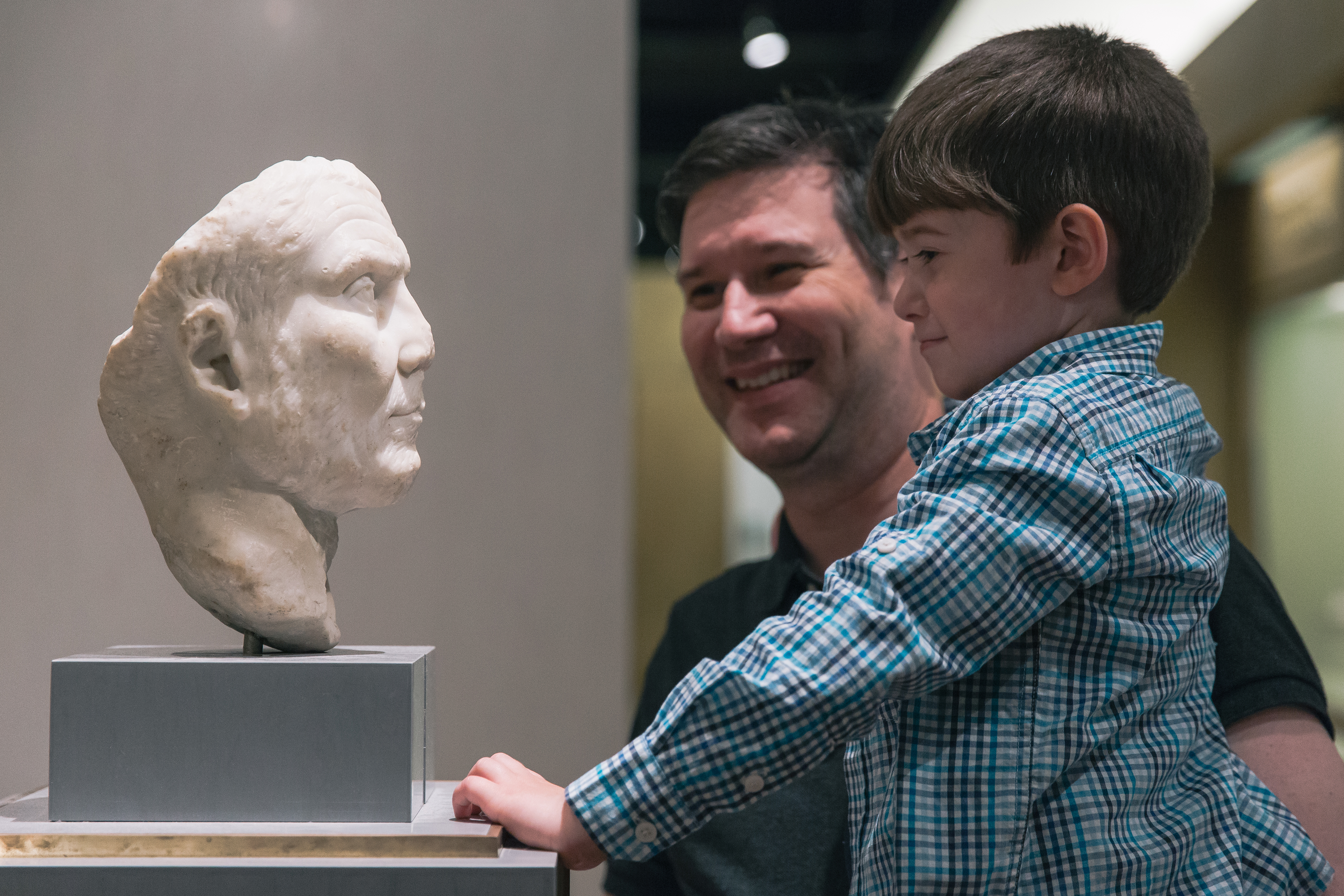 Père et fils appréciant la sculpture ROM