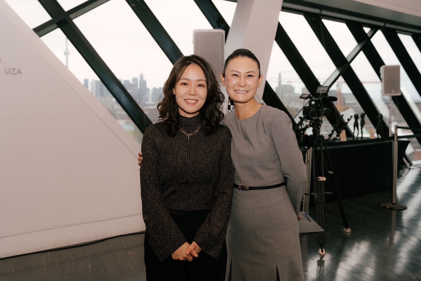 Two women, Hyon Chu Lee and Dr. Vicki Sung-yeon Kwon, stand side by side at the Korea Gallery gift announcement at the Royal Ontario Museum. Both are dressed formally and smiling warmly. The background features museum signage and elegant display cases.
