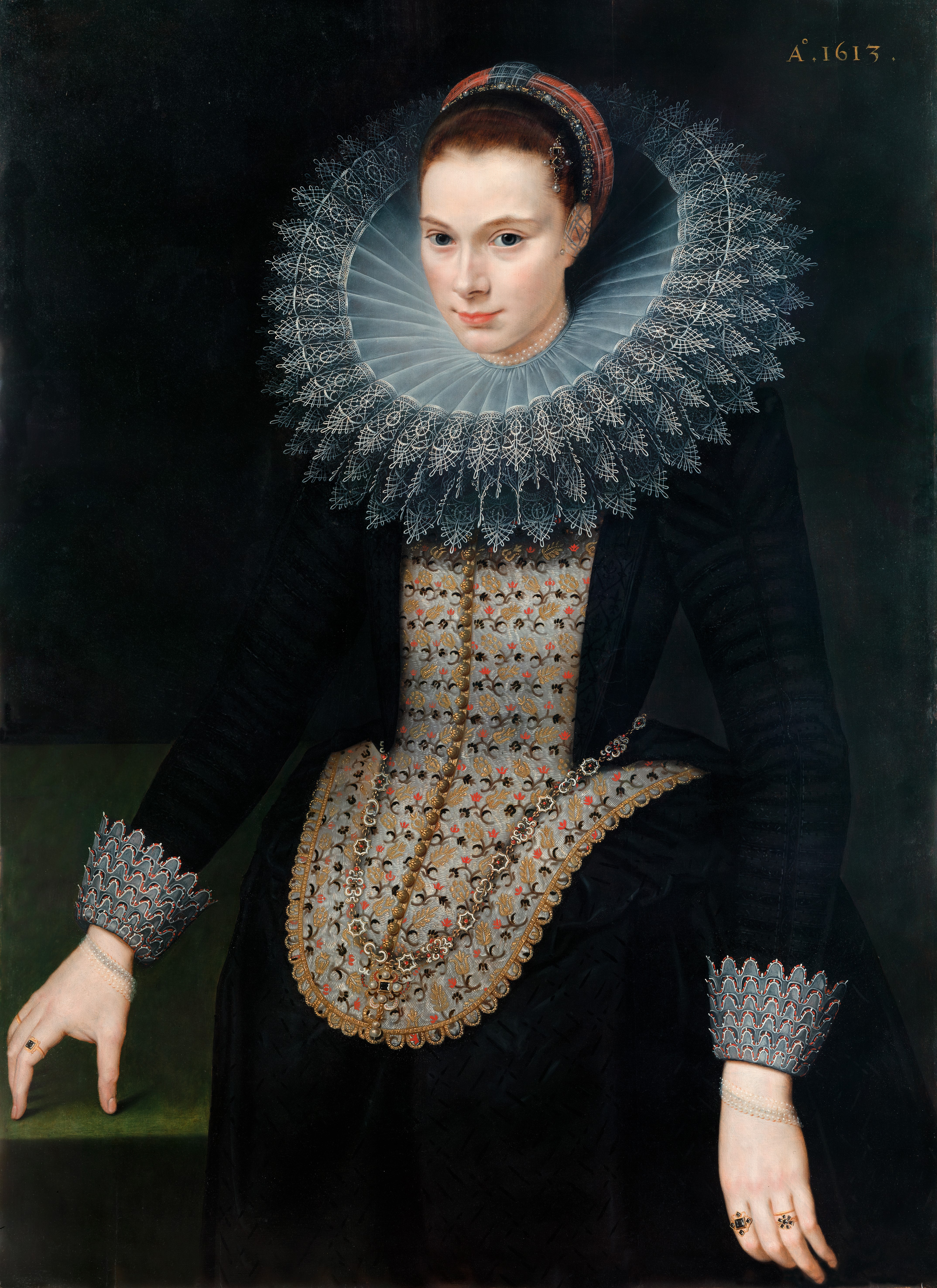 Portrait of a woman in a black dress with a large white lace "ruff" collar, on a black background.