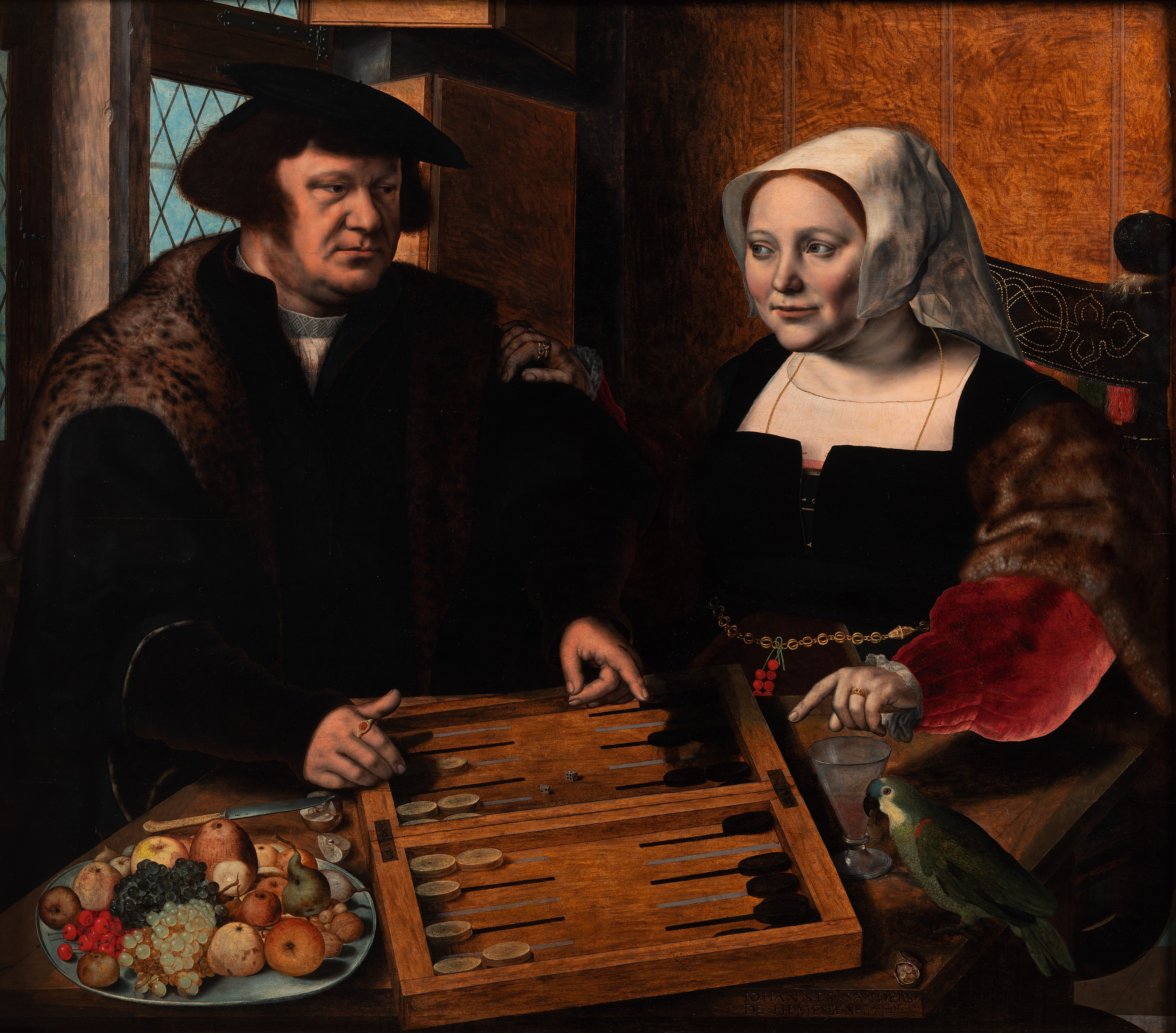 A well dressed couple sit at a table conversing and playing a board game.