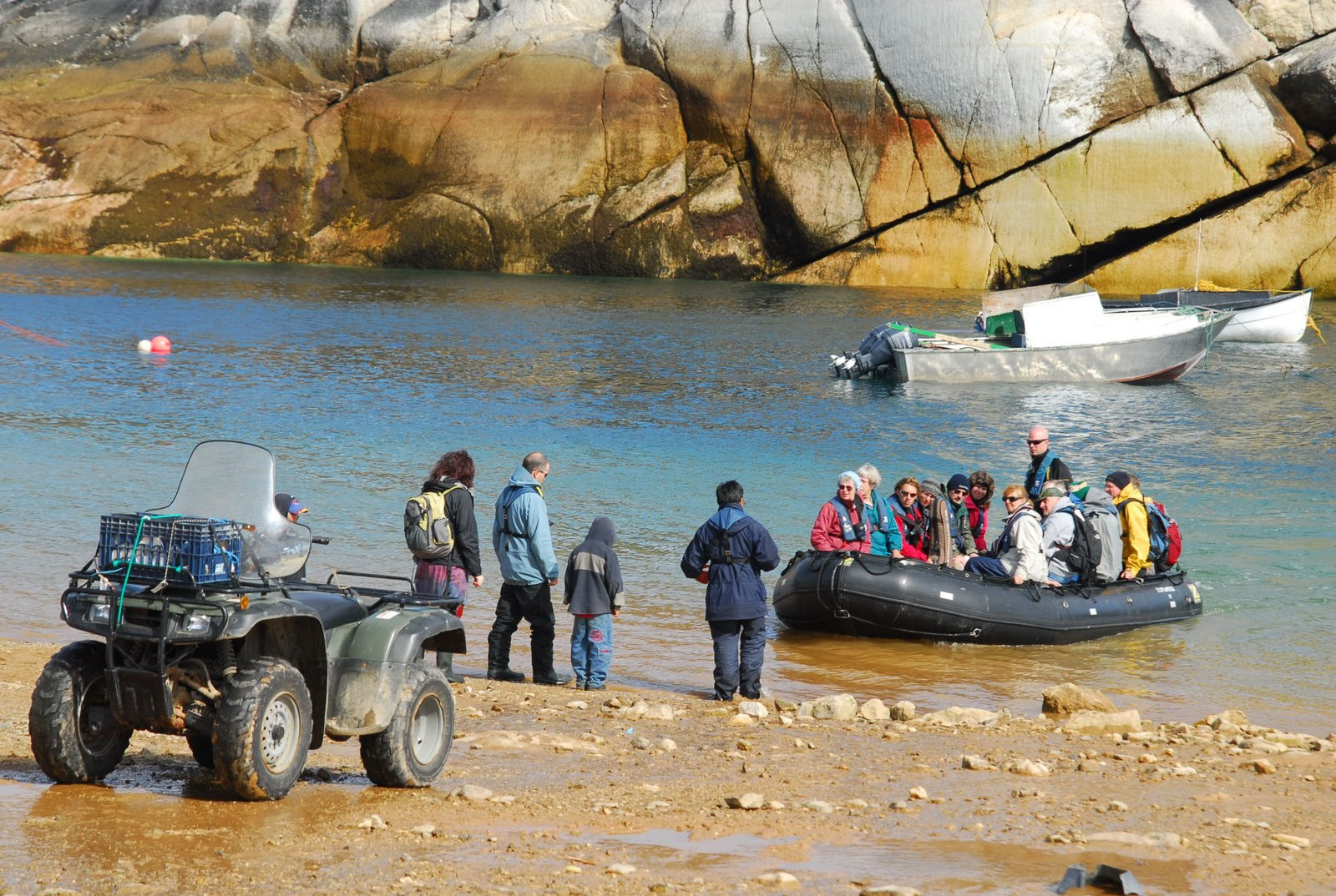 A group of people in a Zodiac boat arriving at shore.
