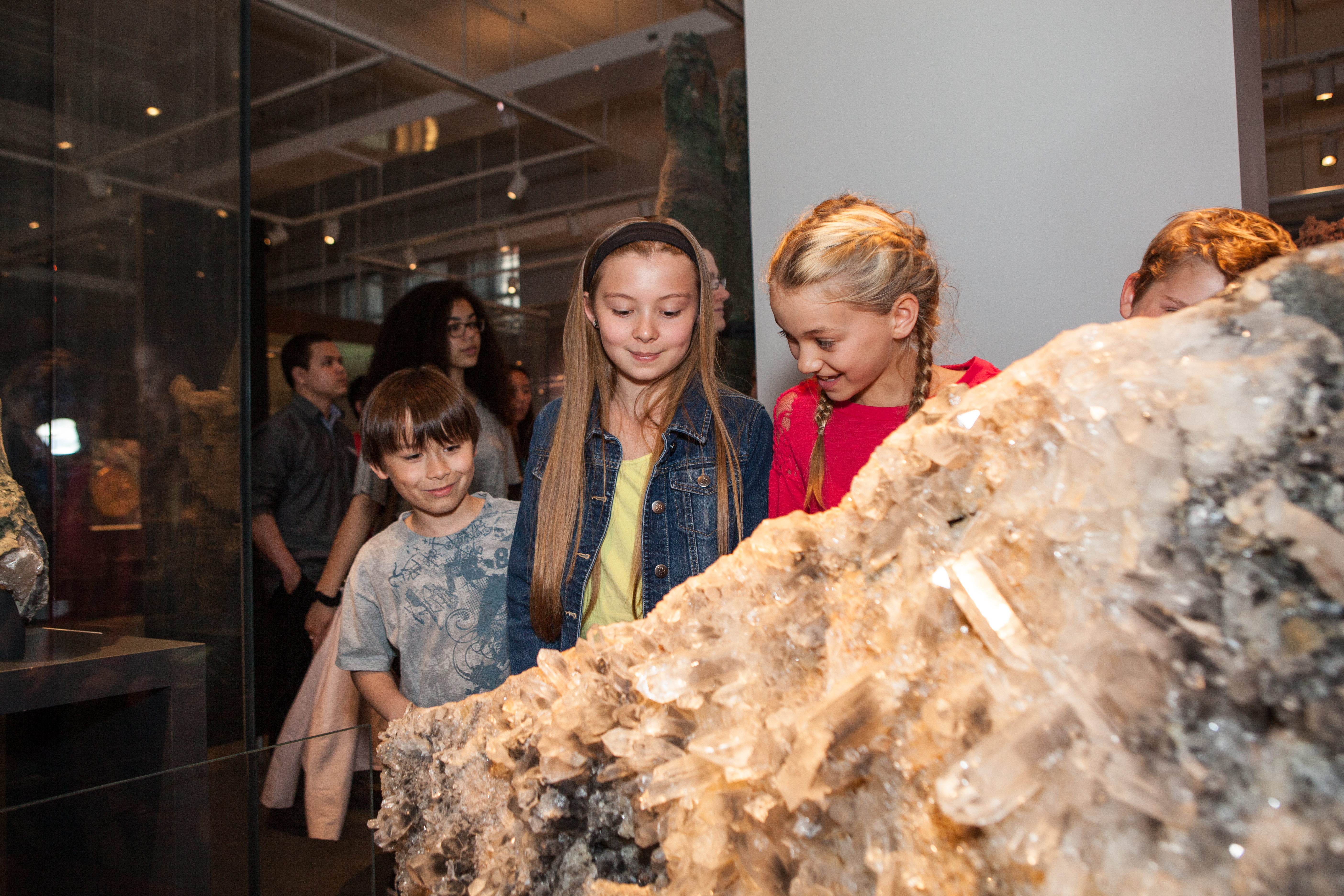 Three young students look at a giant rock