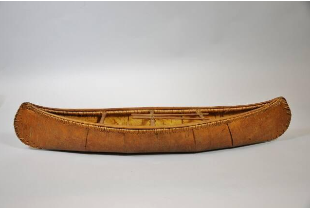 A 68 cm model of a birch bark canoe, showing intricate and accurate details including spacers, paddles, and spruce root stitching the bark to the frame.