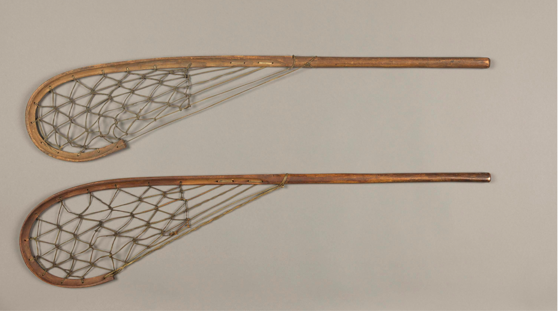 Two long wooden sticks that curve at the end. Within the curve, attaching to a point about midway down the stick, is a lattice of knotted strings made of hide.