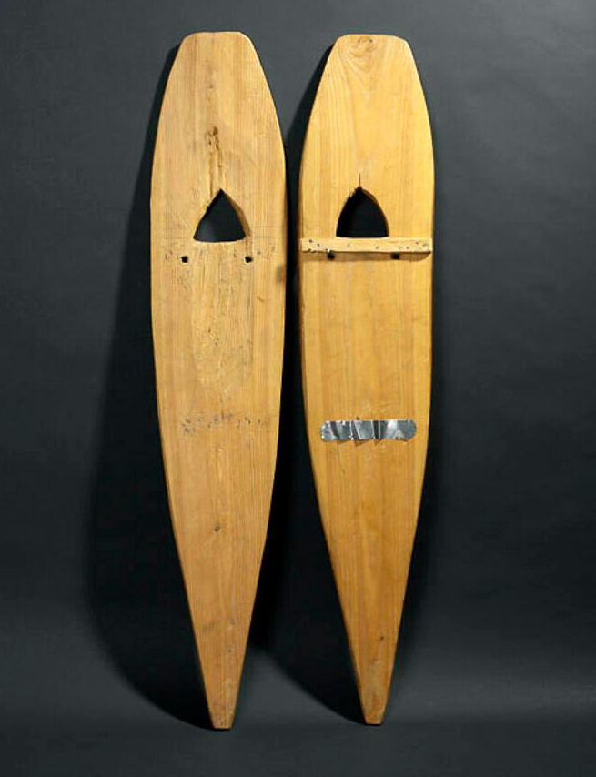 Two snowshoes made of pale wood carved into an oblong shape with pointed ends.