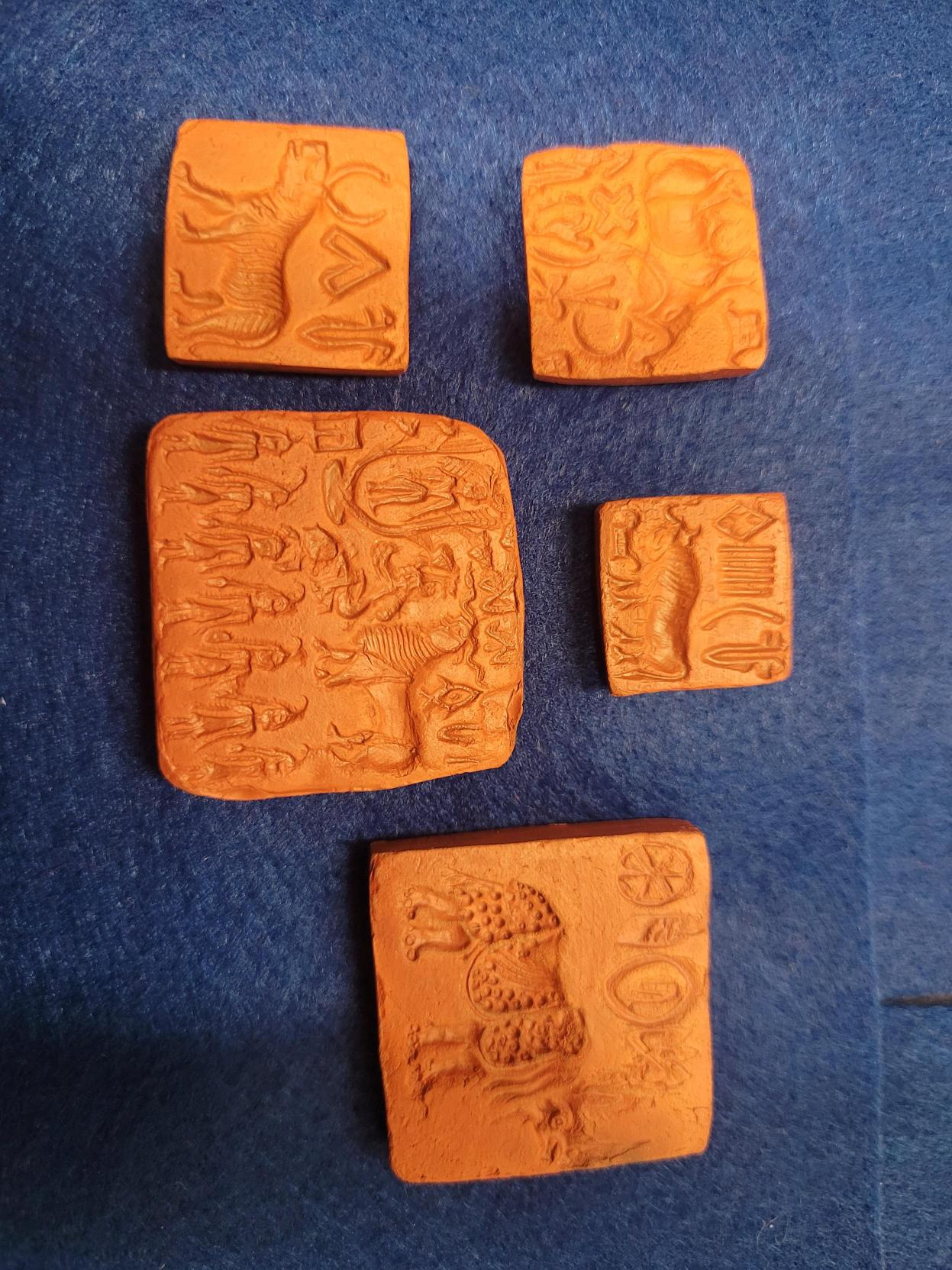 Five orange square seals of various sizes. Each orange square seal has various symbols and images engraved into them.