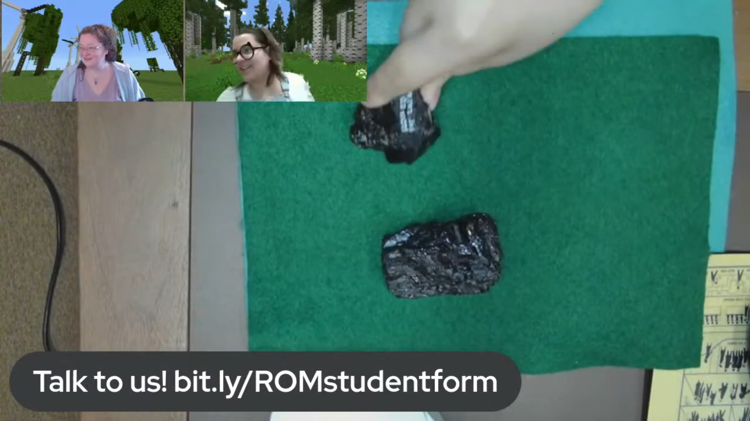 A desktop view of two pieces of coal on green felt. Two facecams of smiling women are in the top right of the image.