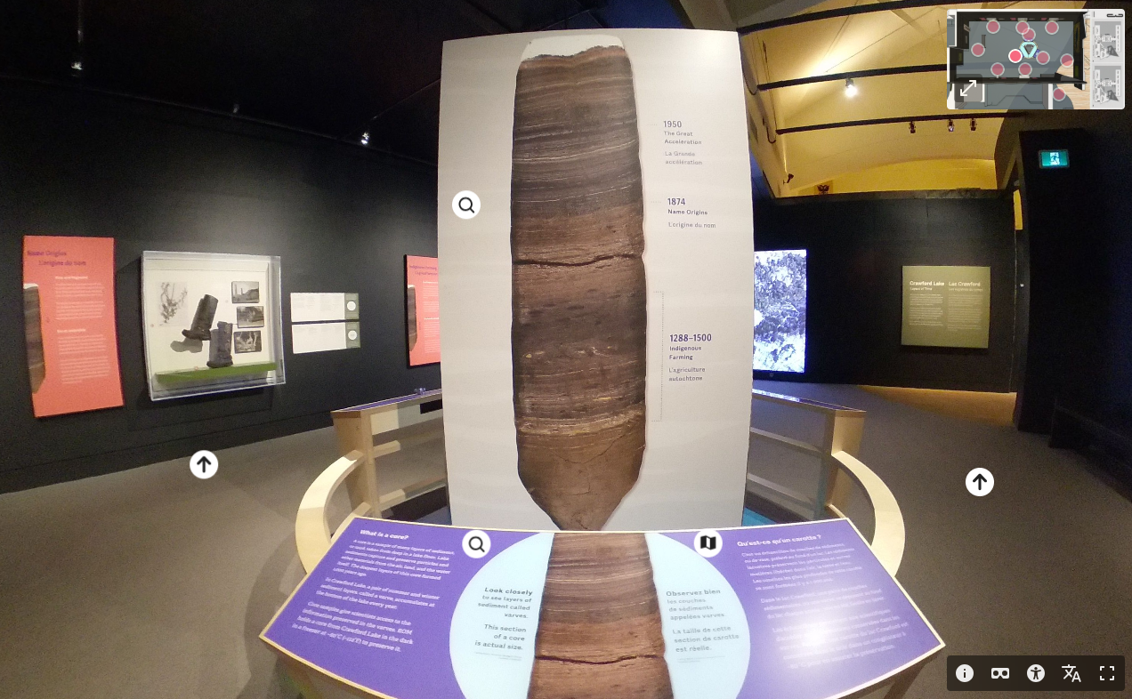 A display in the centre of a museum gallery with dark walls shows a core sample with layers of deposits in various shades of brown and black.