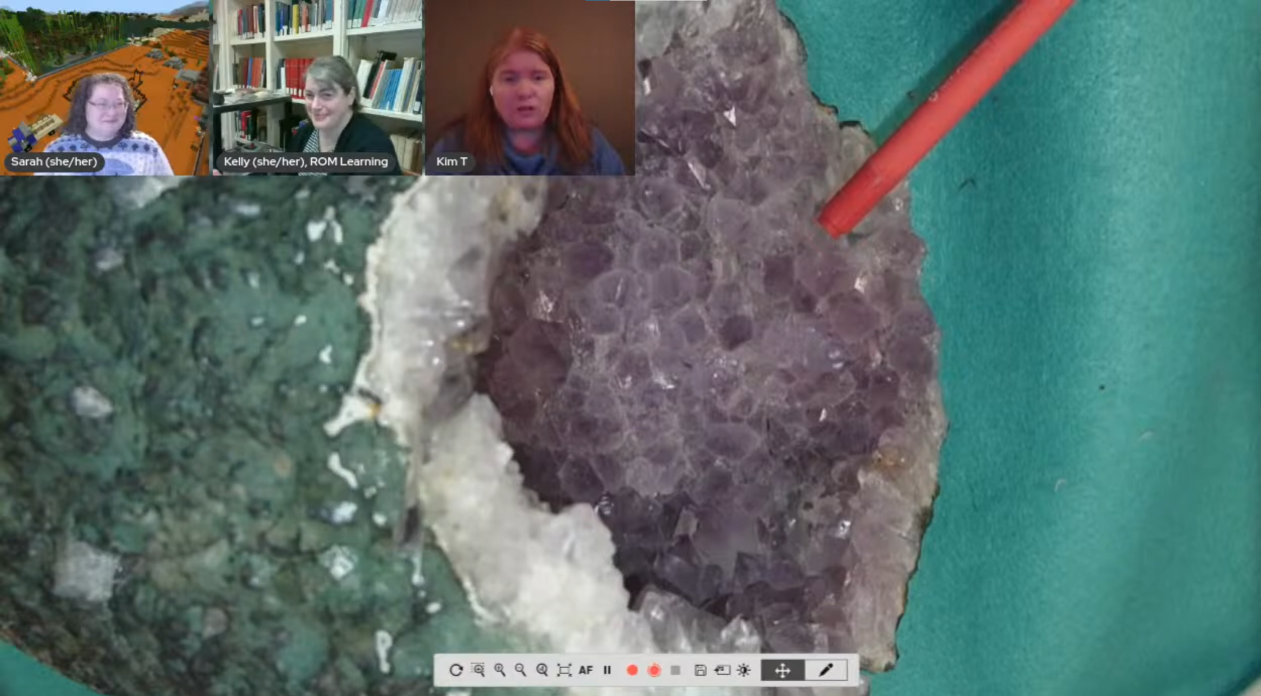 A desktop camera shows a sparkling geode with a greenish basalt exterior and a purple crystal interior.