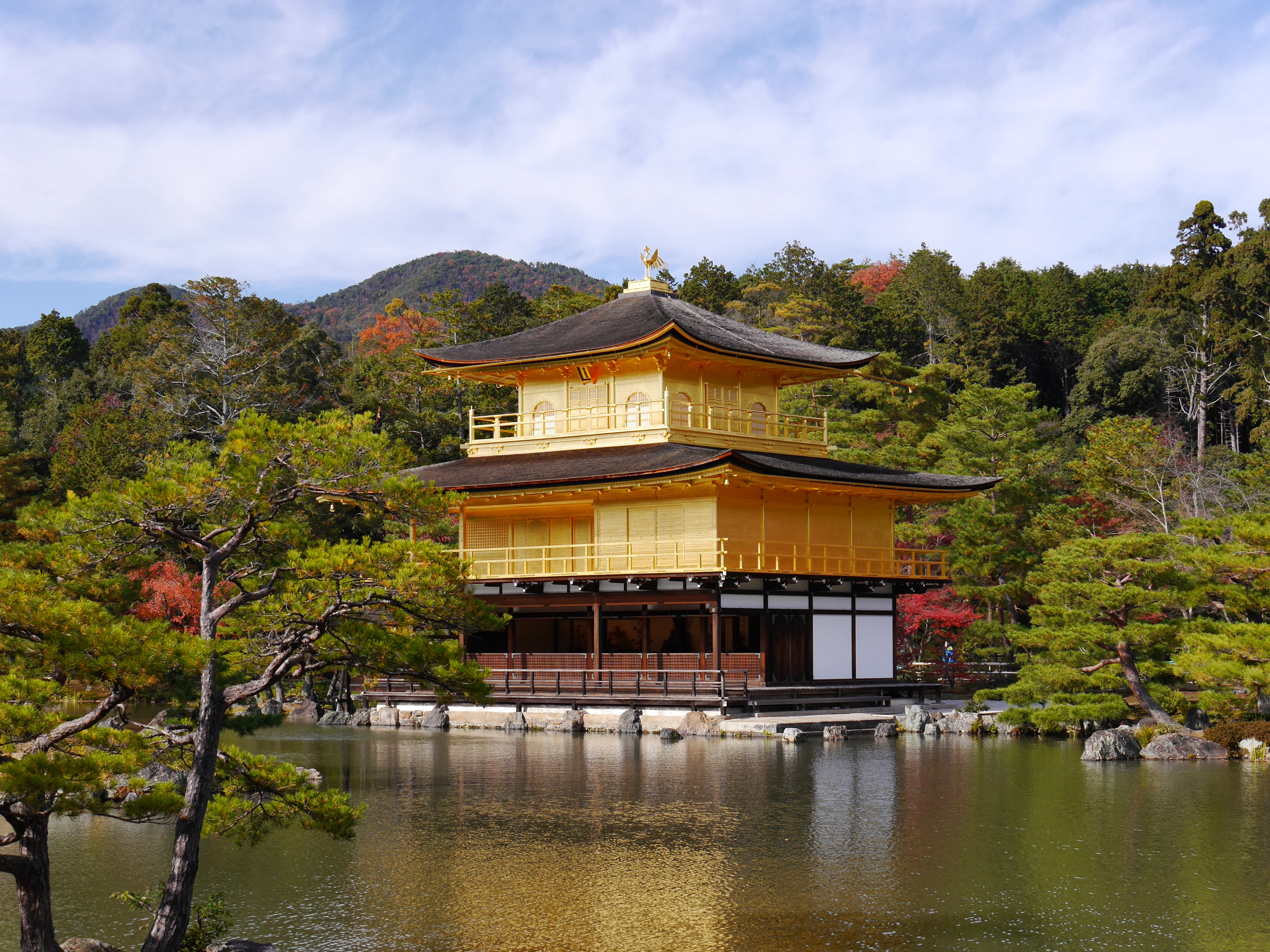 A golden pagoda-style building on the shore of a lake.