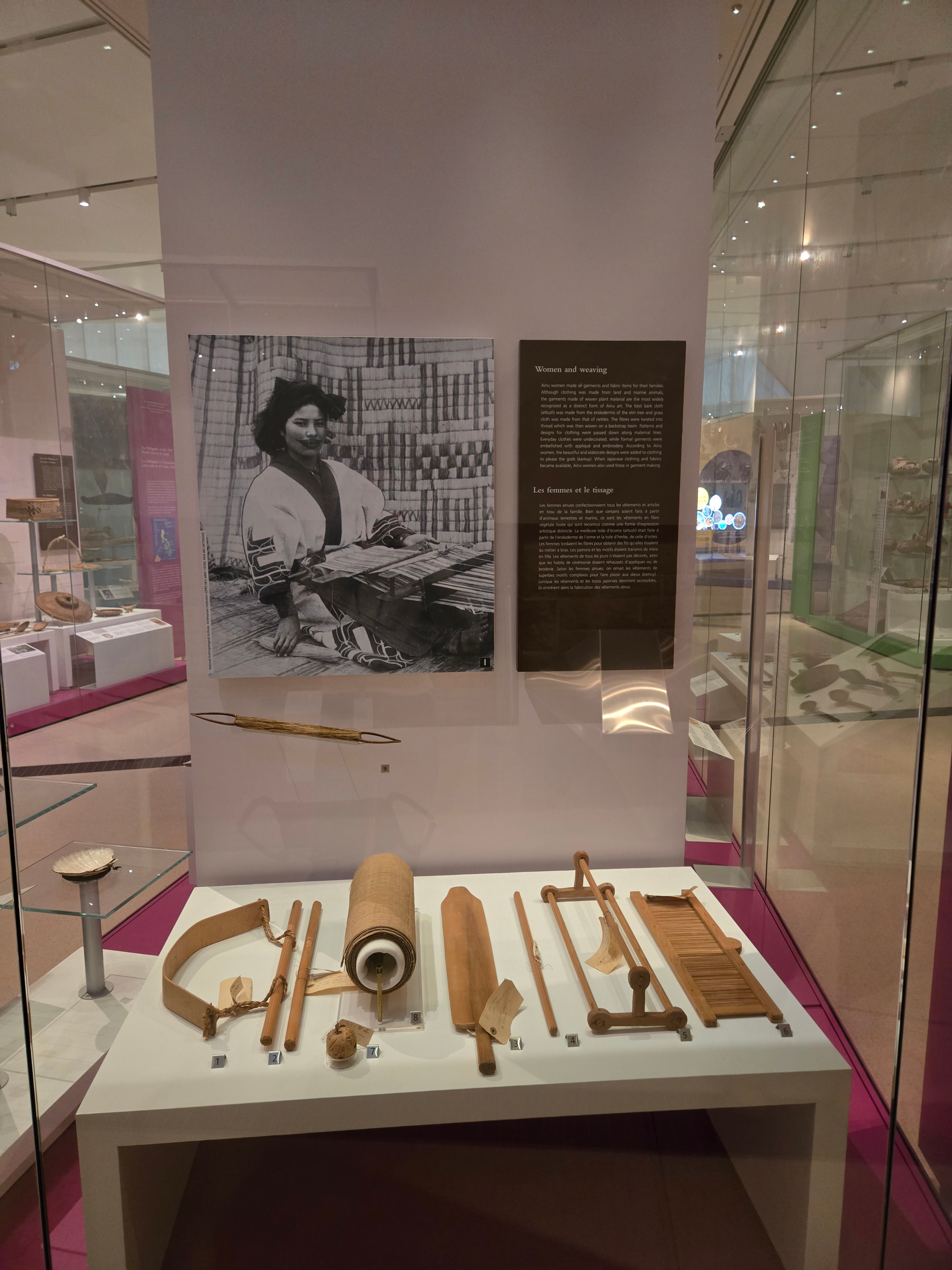 A case in a museum gallery holds a variety of wooden weaving tools.