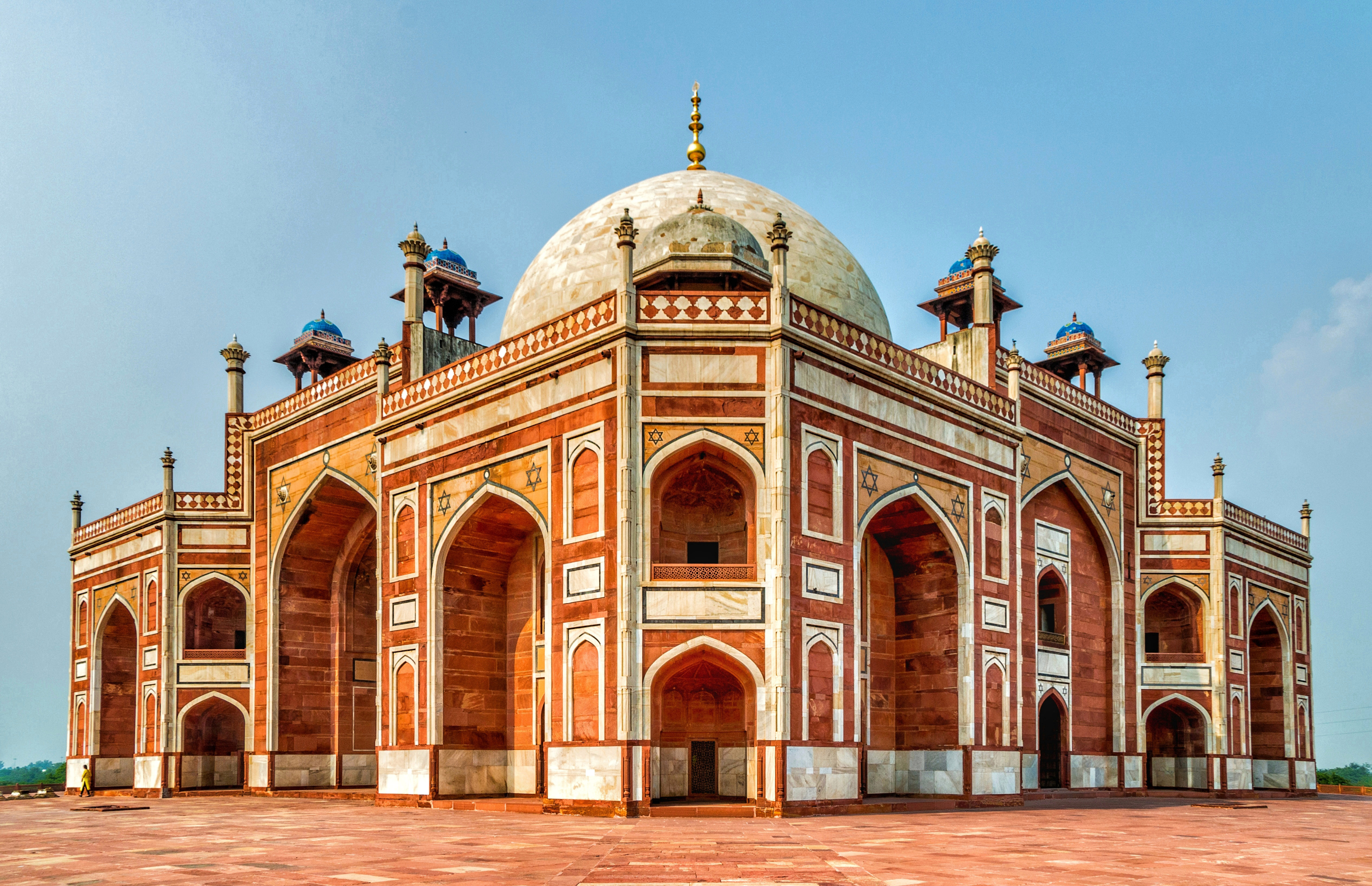 A large red brick building with palm trees in the foreground
