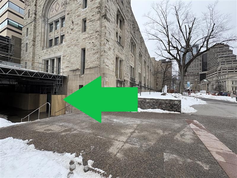 A green arrow points at doors located beneath and between scaffolding pillars