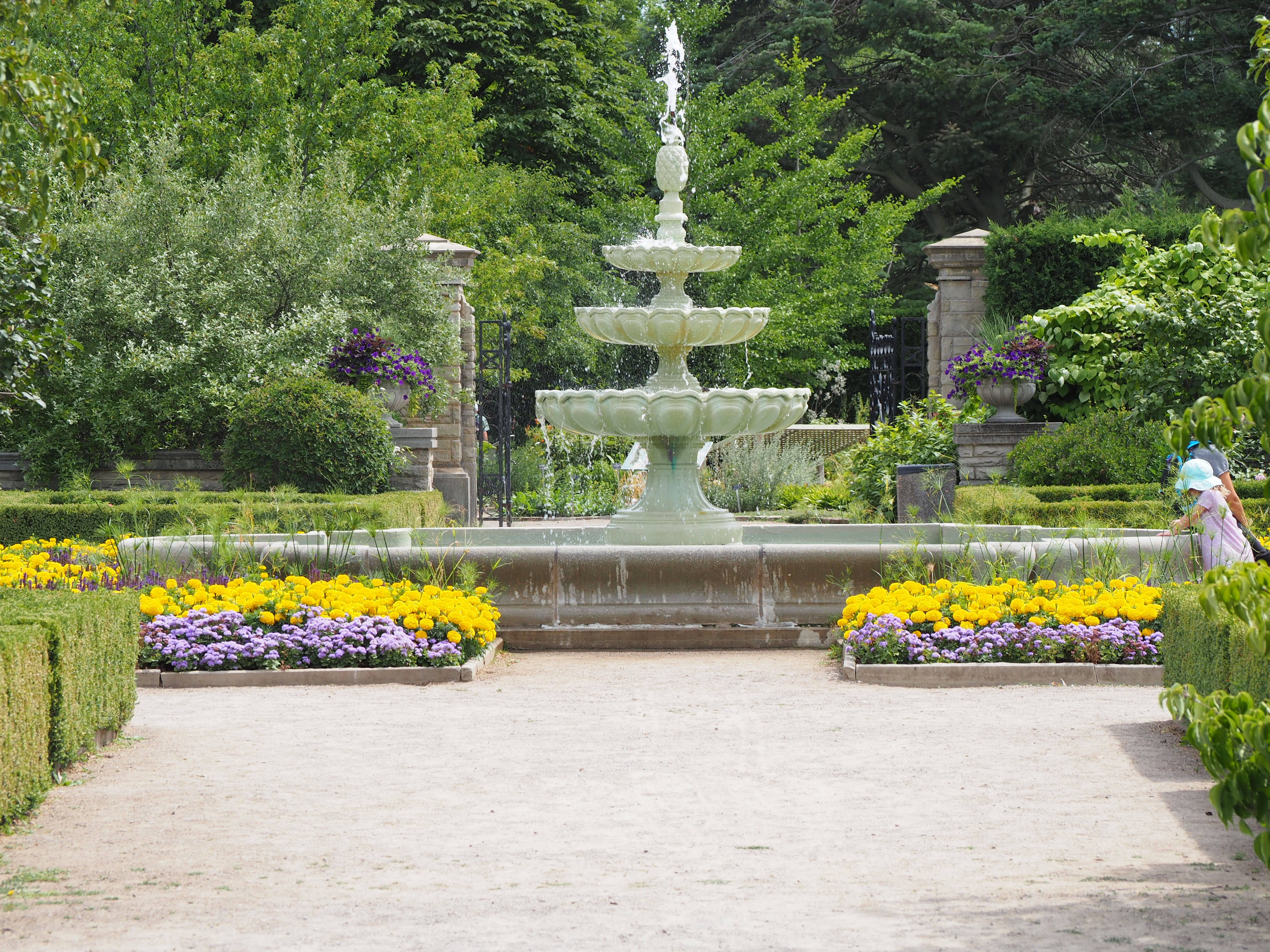 Fountain in background with flowers and walking path in foreground.