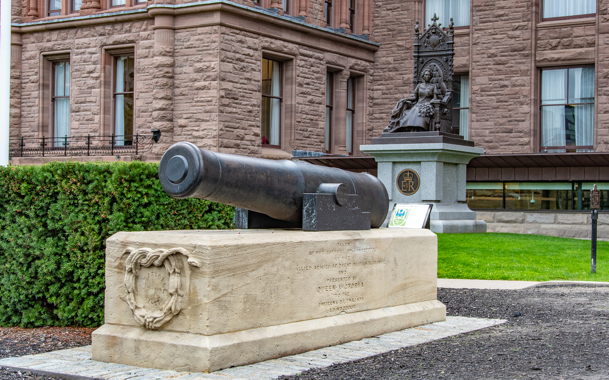Canon in foreground with statue and building in background