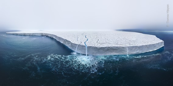 Un grand iceberg flottant dans l'eau sombre de l'océan sous un ciel clair.