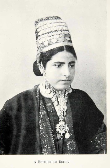 A bride from Bethlehem wears a coin headdress (shatweh) atop her head, held in place   with an elaborate chin-chain (iznaq). Photograph (reproduction), 1904. Photo © ROM