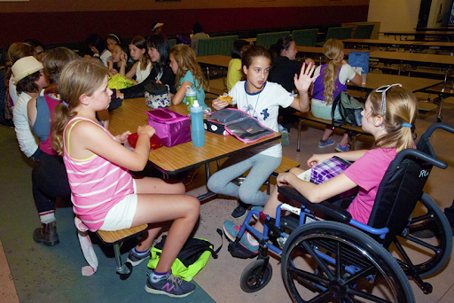 Students sit having lunch at long tables