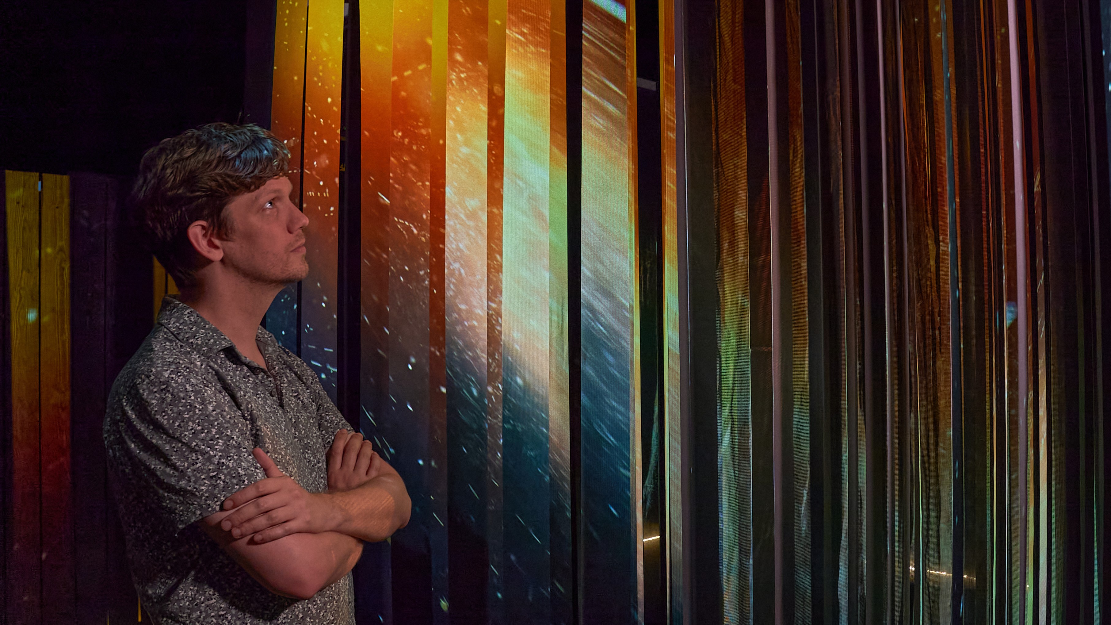 A person experiences light playing off tall vertical panels.