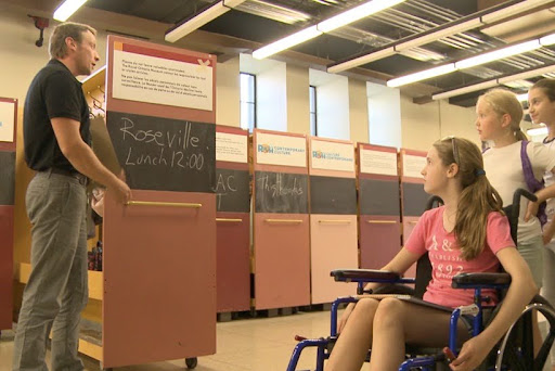 Students look at a man standing next to an open locker