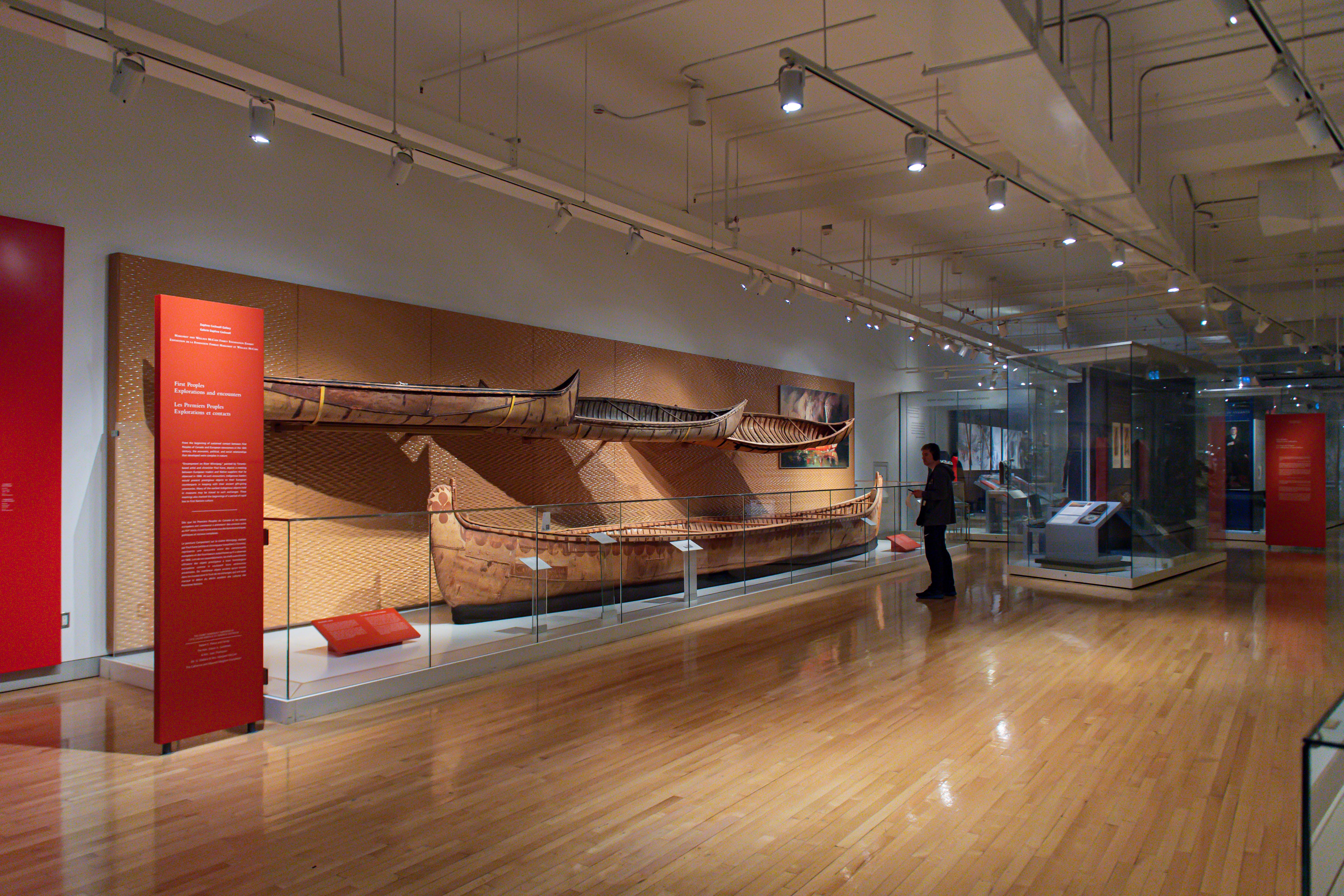 A man standing in front of a display of four birchbark canoes.