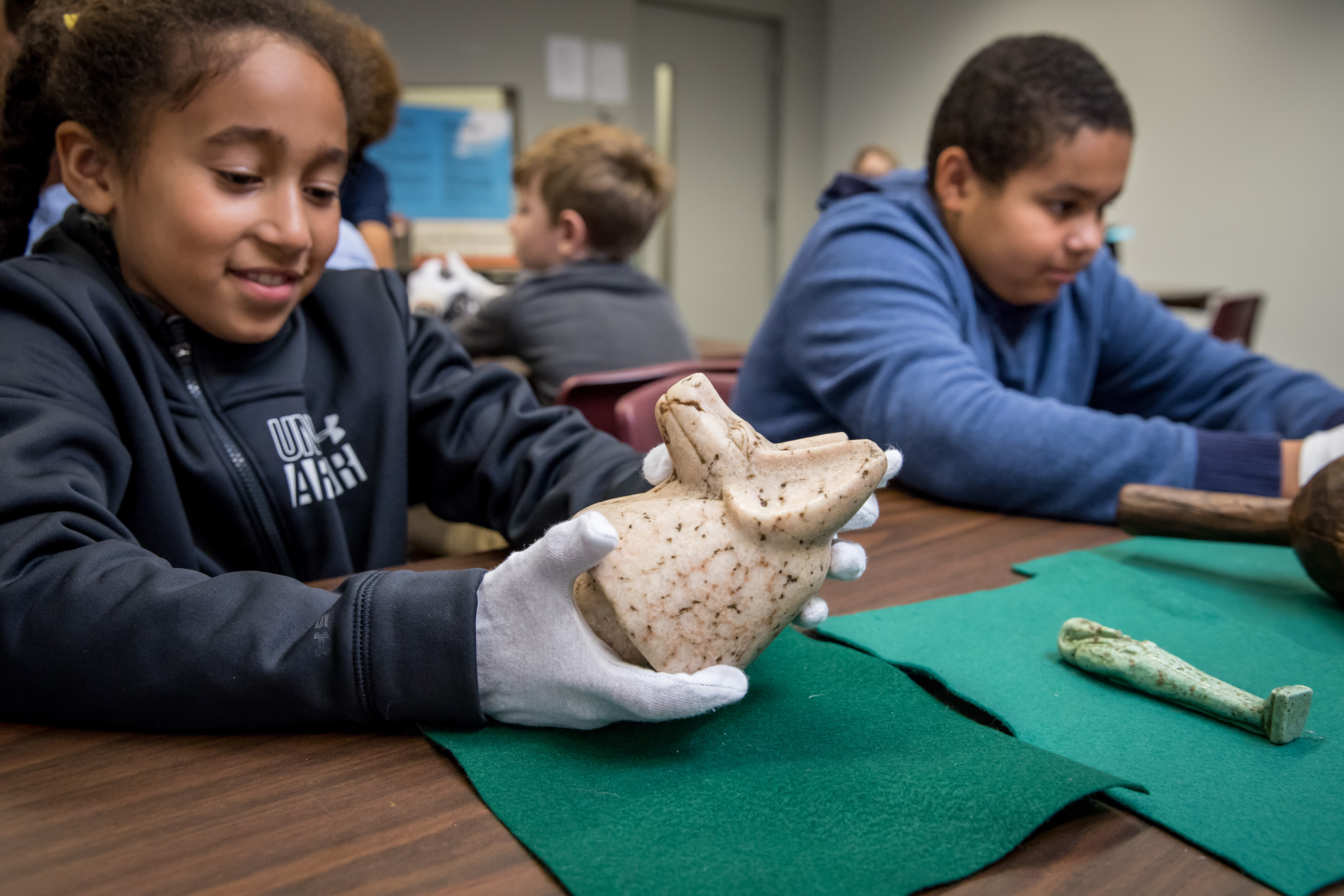A student holds an ancient Egyptian canopic jar lid.