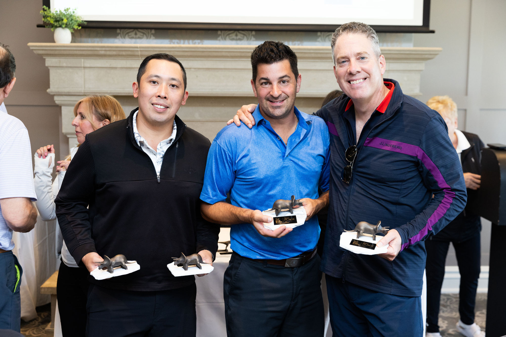3 men holder the 3rd place foursome trophies. 