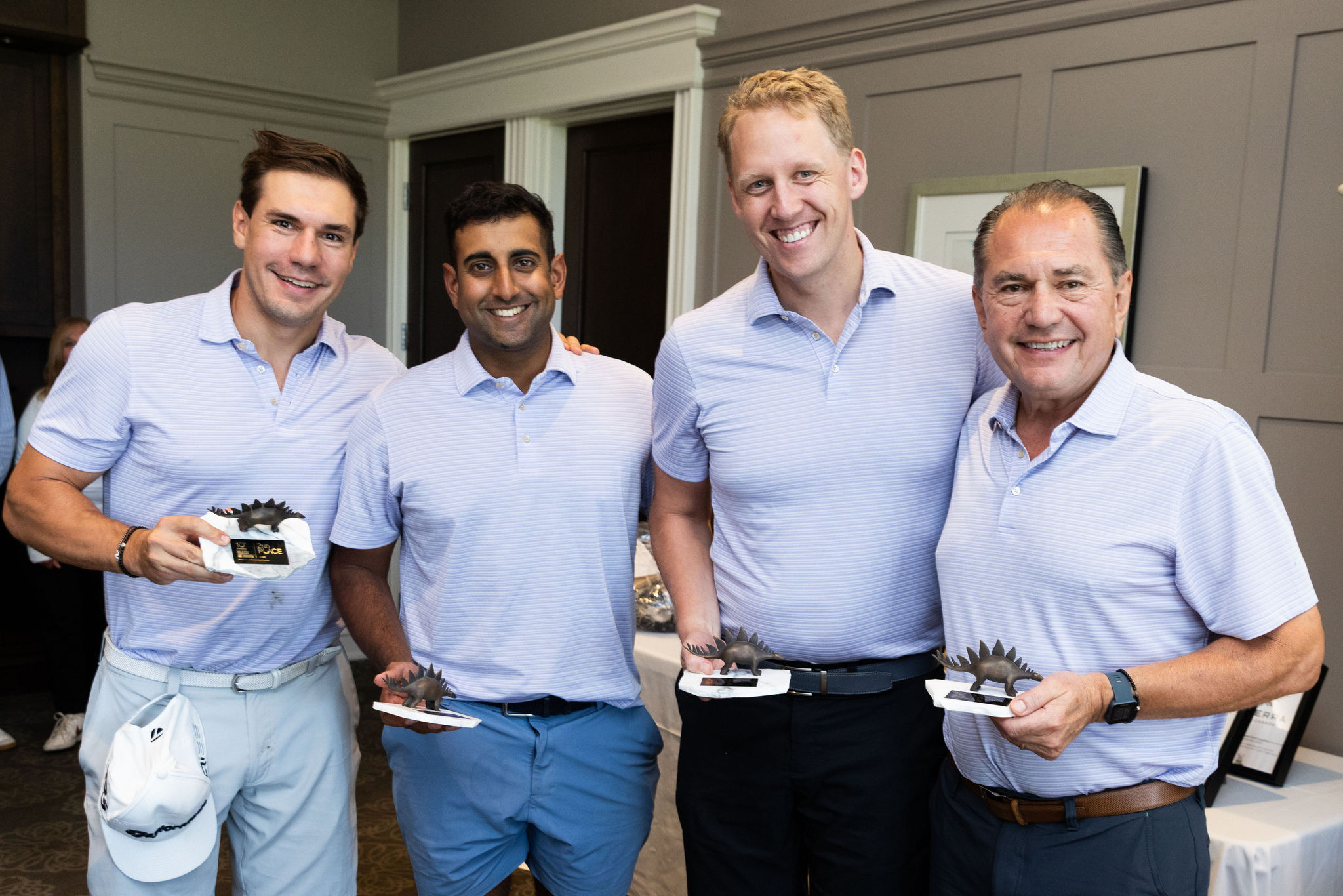4 men holding the 2nd place foursome trophies. 