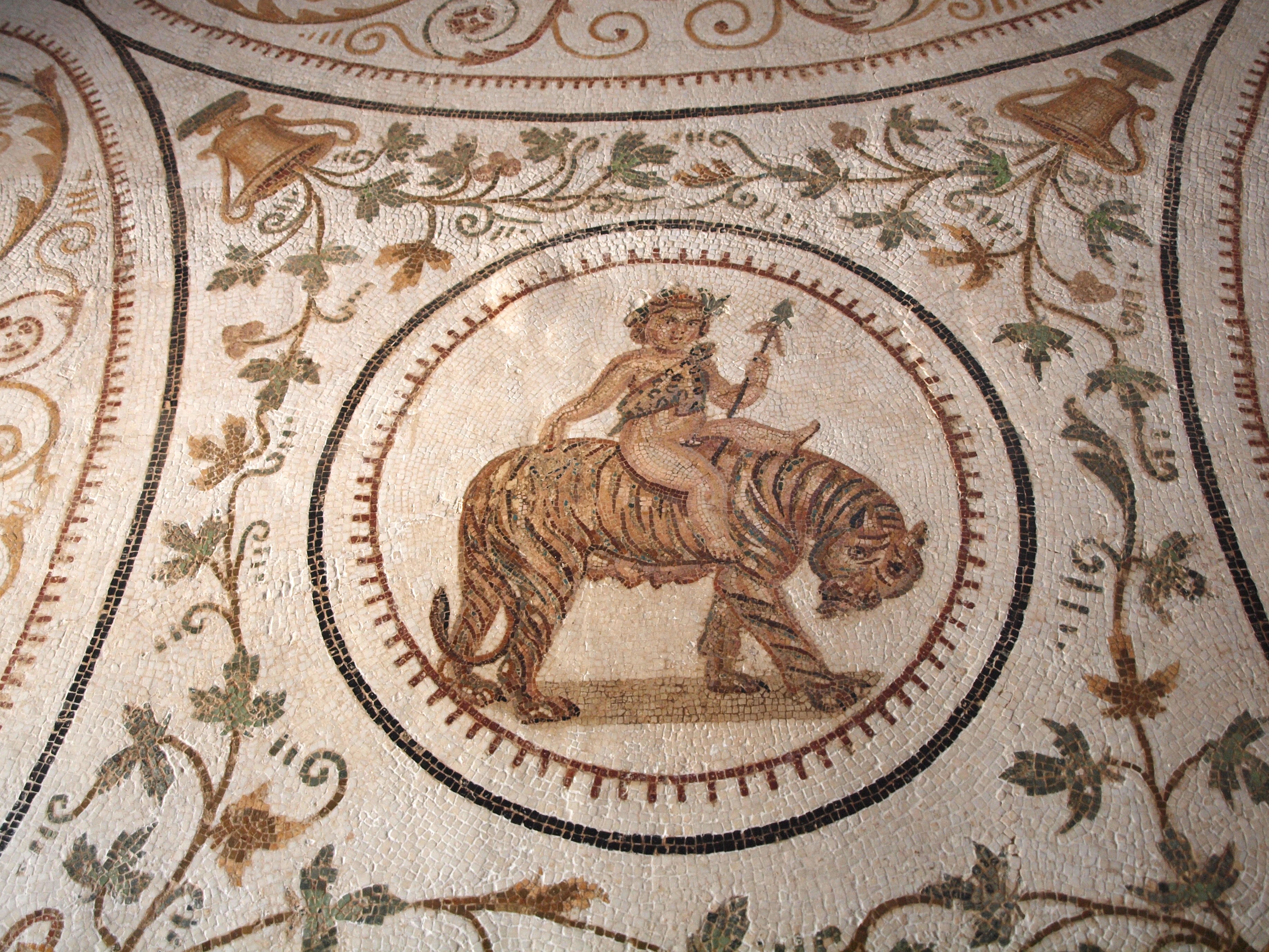 A mosaic featuring a central figure of a young boy riding a tiger, surrounded by intricate floral and geometric patterns