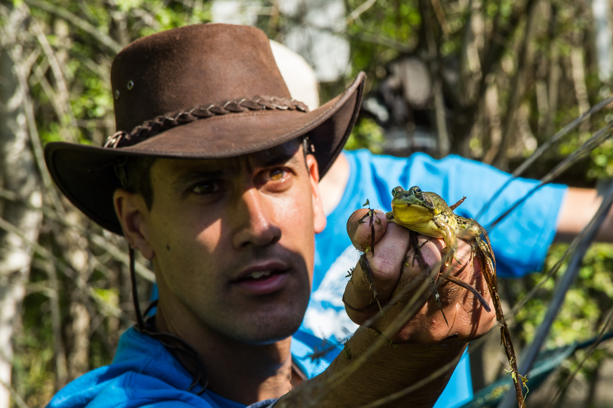 A man reaches out to show volunteers a frog he has caught.