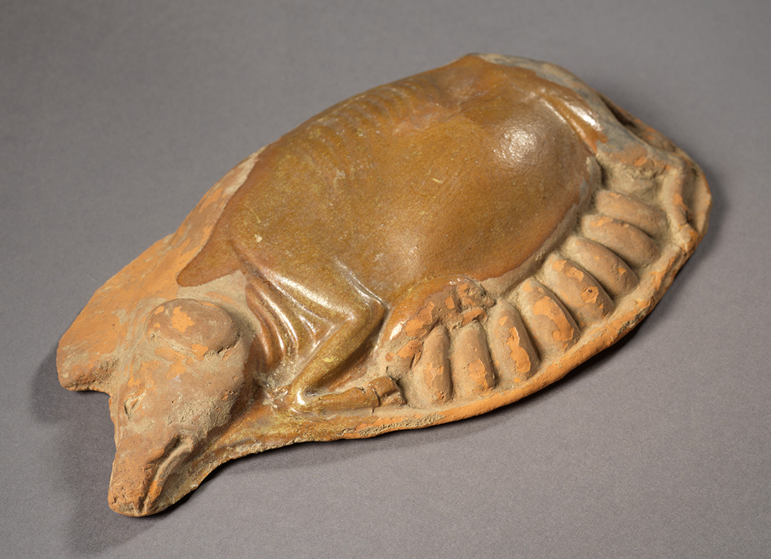 Figurine orangée représentant une truie couchée sur le côté qui allaite huit porcelets