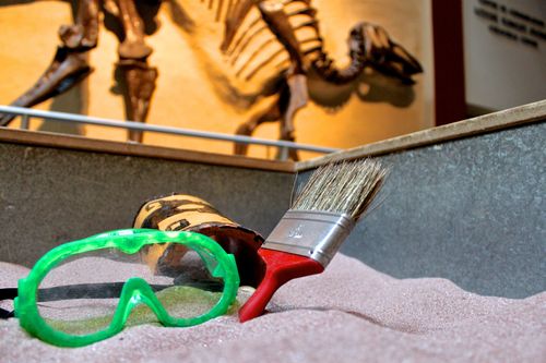 Reproduction archaeology dig with dinosaur in the background.