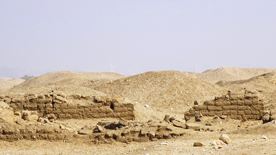 Falling down brick walls stand in a desert landscape. 