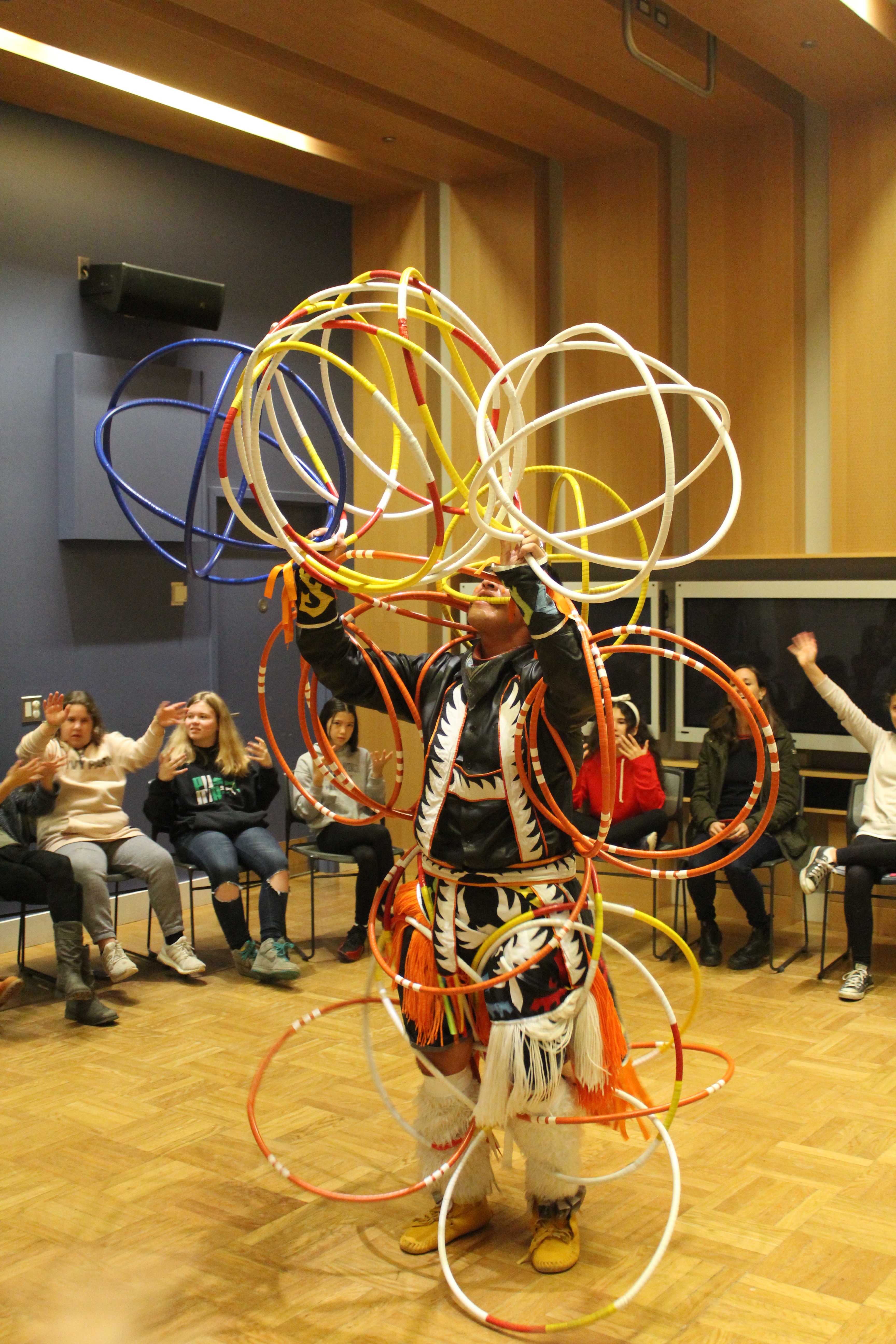 A man in traditional costume performs with hoops