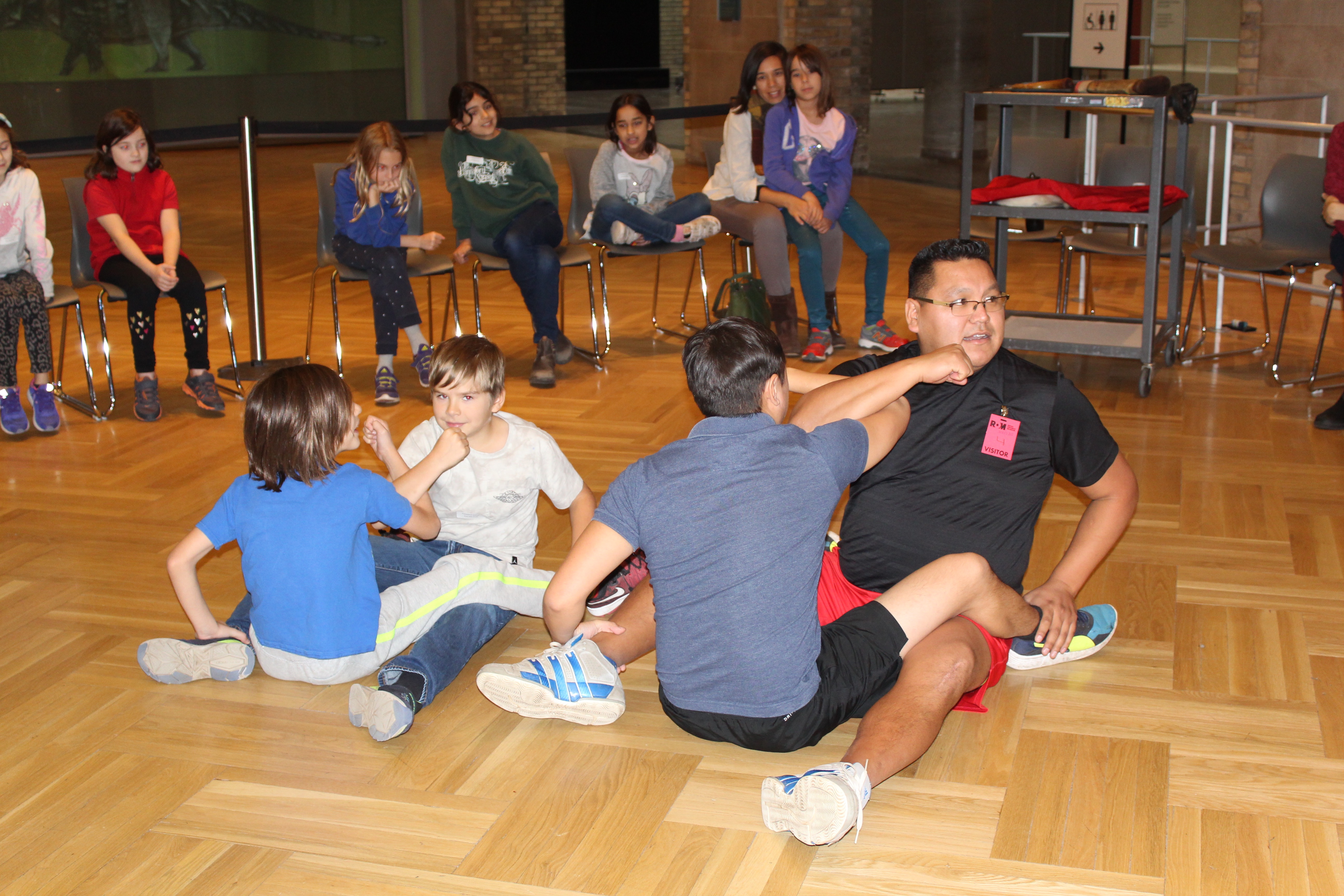 Two pairs of people wrestling on a hardwood floor