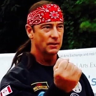 an indigenous man wearing a red headband stands with his fist raised