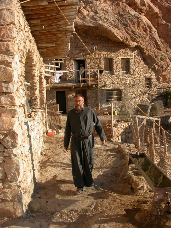 Father Paolo Dall'Oglio in the new buildings in 2004, behind him is a large cave that may actually have been the original focus of the complex.
