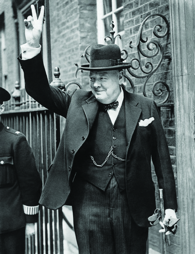 A black and white photograph of a man in a bowler hat and holding up his fingers in a peace sign