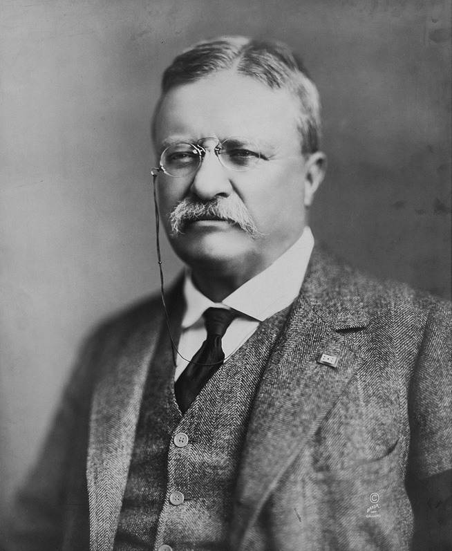 Black and white photograph of a man in a three piece suit and a moustache 