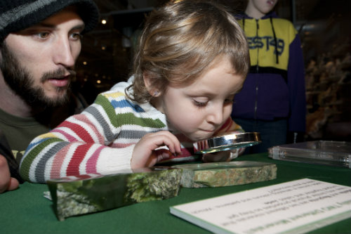 A girl looks at a mineral through a magnifying glass.