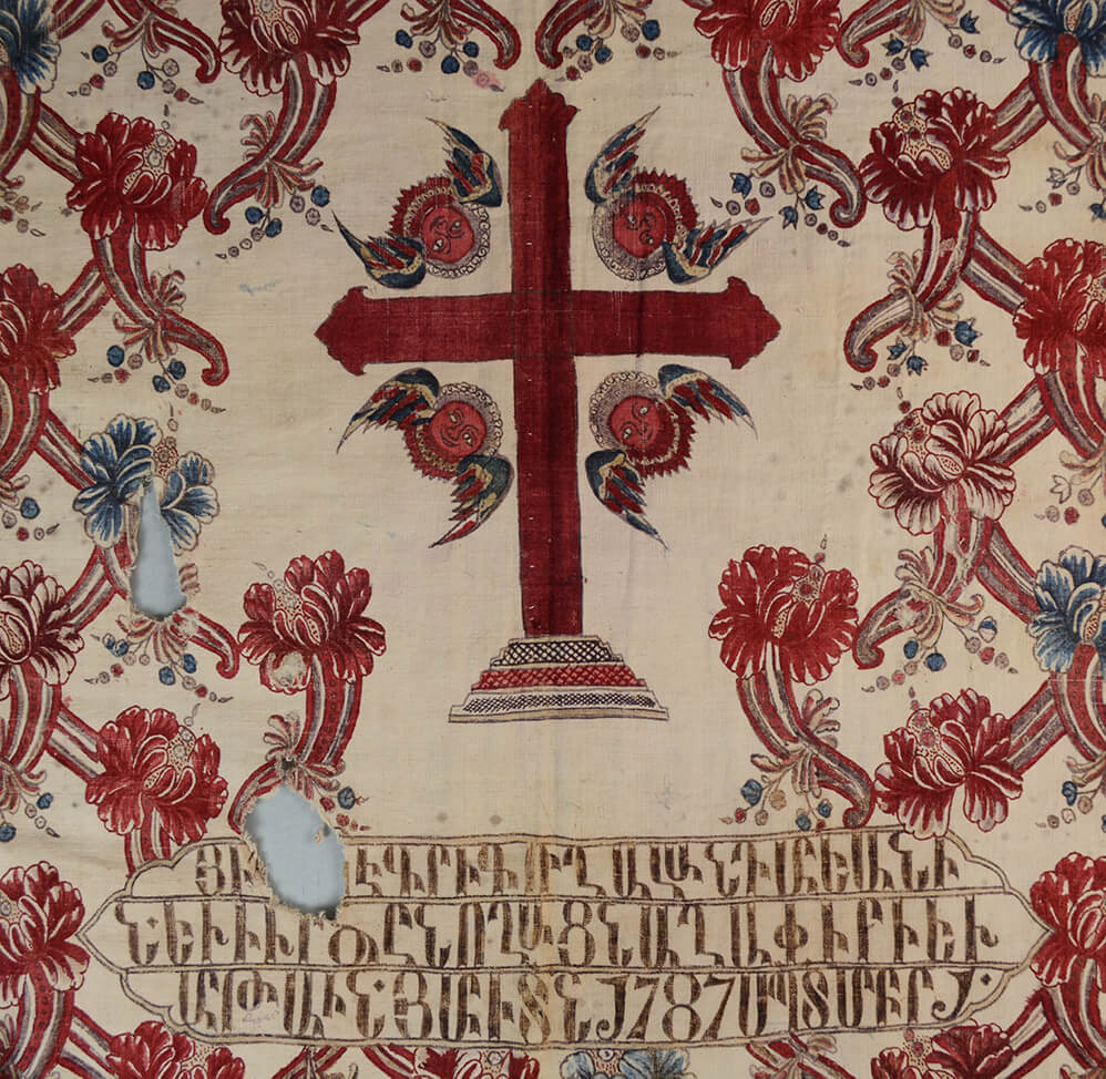 A detail from the centre of the cope showing a large cross and an inscription below in Armenian script. 