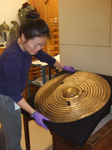 Woman holding a metal shield in her hands